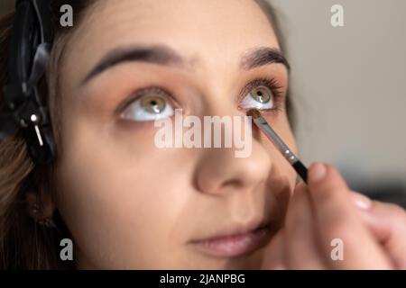 Maquilleuse application de l'ombre oculaire à la paupière inférieure d'une fille avec un pinceau. Photo de haute qualité Banque D'Images