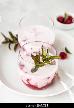 Deux verres avec boisson fraîche d'été. Sauce à la framboise et smoothie au babeurre décorés de feuilles de menthe poivrée fraîche. Des mets sucrés maison Banque D'Images