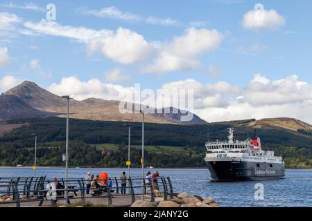 Le ferry des îles Caledonian arrive au port de Brodick avec la montagne Goatfell en arrière-plan Banque D'Images