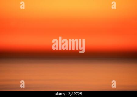 Détail abstrait de la mer floue avec le ciel bleu orangé au-dessus de l'horizon sombre. Chaîne anglaise, Royaume-Uni. Banque D'Images