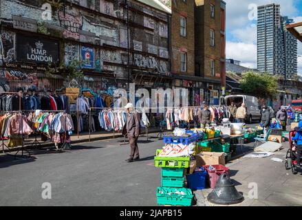 Un homme âgé passe devant une cabine de vêtements de seconde main au marché de Brick Lane à l'est de Londres, au Royaume-Uni Banque D'Images