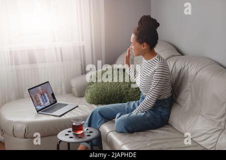 Vue de dessus de la bonne femme de course mixte assis sur un canapé vidéo chat en ligne sur un ordinateur portable Banque D'Images