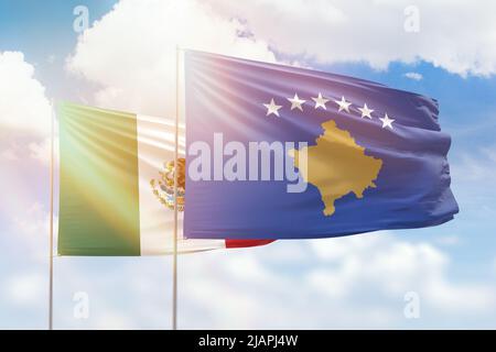 Ciel bleu ensoleillé et drapeaux du kosovo et du mexique Banque D'Images