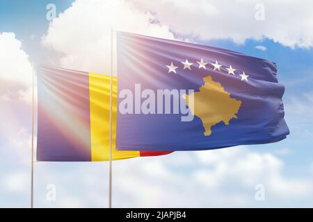 Ciel bleu ensoleillé et drapeaux du kosovo et de la roumanie Banque D'Images