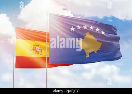 Ciel bleu ensoleillé et drapeaux du kosovo et de l'espagne Banque D'Images