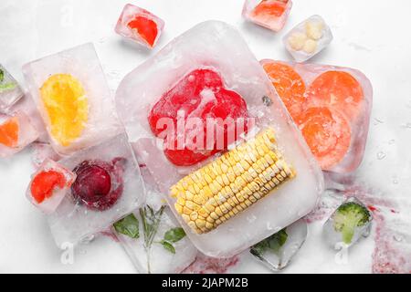 Légumes frais congelés dans de la glace sur fond clair Banque D'Images