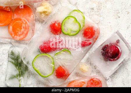 Légumes frais coupés congelés dans de la glace sur fond clair Banque D'Images