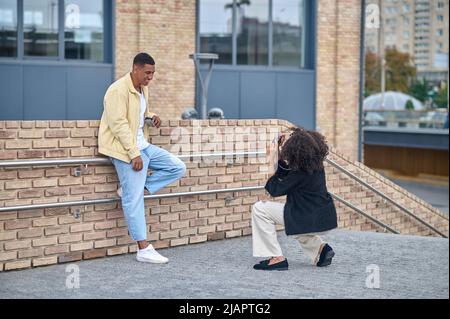 Une jeune fille s'est enroulée pour photographier un homme qui pose dans la rue Banque D'Images