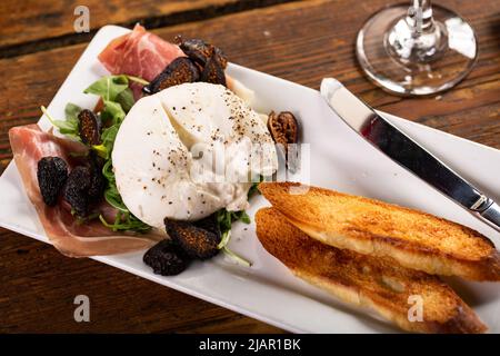 Hors-d'œuvre burrata avec prosciutto, figues séchées et pain grillé Banque D'Images