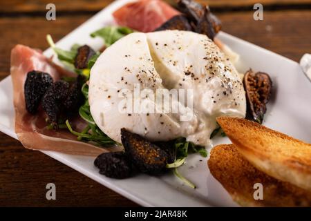 Hors-d'œuvre burrata avec prosciutto, figues séchées et pain grillé Banque D'Images