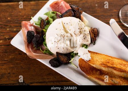 Hors-d'œuvre burrata avec prosciutto, figues séchées et pain grillé Banque D'Images