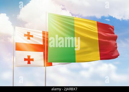 Ciel bleu ensoleillé et drapeaux du mali et de la géorgie Banque D'Images