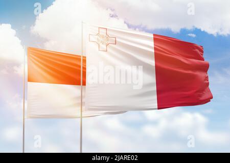 Ciel bleu ensoleillé et drapeaux de malte et d'indonésie Banque D'Images