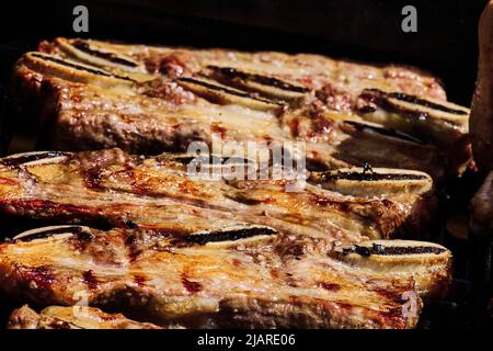 côte de bœuf juteuse et côte de porc lentement sur le gril au feu d'un barbecue à gaz Banque D'Images