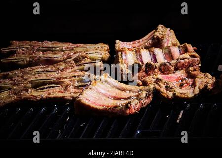 côte de bœuf juteuse et côte de porc lentement sur le gril au feu d'un barbecue à gaz Banque D'Images