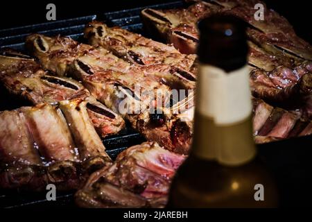 côte de bœuf juteuse et côte de porc lentement sur le gril au feu d'un barbecue à gaz Banque D'Images