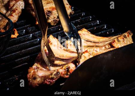 côte de bœuf juteuse et côte de porc lentement sur le gril au feu d'un barbecue à gaz Banque D'Images