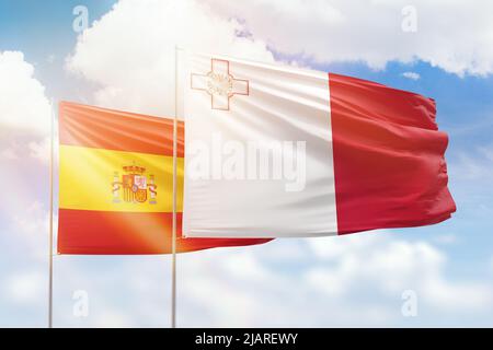 Ciel bleu ensoleillé et drapeaux de malte et d'espagne Banque D'Images