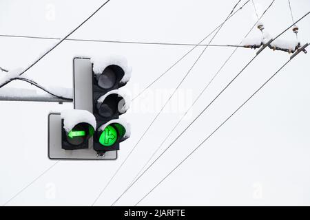 Feu de circulation avec un panneau vert contre le ciel en hiver dans la neige dans la ville en Ukraine Banque D'Images