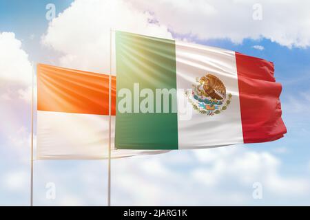 Ciel bleu ensoleillé et drapeaux du mexique et de l'indonésie Banque D'Images