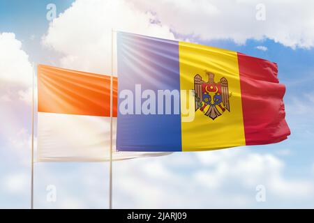 Ciel bleu ensoleillé et drapeaux de la moldavie et de l'indonésie Banque D'Images