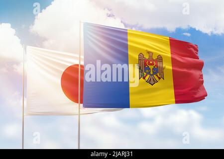 Ciel bleu ensoleillé et drapeaux de la moldavie et du japon Banque D'Images