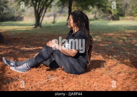 Une femme a vu s'asseoir sur les feuilles tombées de l'arbre pendant l'automne Banque D'Images