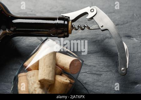 Tire-bouchon en inox dans un bouchon de bouteille de vin sur fond noir d'ardoise rocheuse. Concept de culture de la vigne Banque D'Images