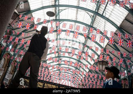 Un animateur de rue se produit devant les foules à Covent Garden alors que les préparatifs se poursuivent pour les célébrations du Jubilé de platine de la Reine dans la capitale, le 31st mai 2022, à Londres, en Angleterre. La reine Elizabeth II est sur le trône du Royaume-Uni depuis 70 ans, le monarque le plus longtemps au service de l'histoire anglaise et les drapeaux de l'Union Jack peuvent être vus partout dans le pays dans la semaine précédant le week-end du Jubilé. Banque D'Images