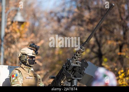 Bucarest, Roumanie - 1 décembre 2021 : un soldat tient une mitrailleuse sur le toit d'un porte-troupes blindé, lors d'un défilé militaire à Buchares Banque D'Images