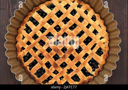 Tarte aux myrtilles maison au treillis fraîchement cuite dans un plat de cuisson sur table en bois Banque D'Images