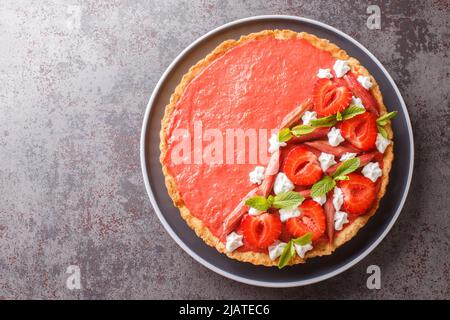 Tarte festive avec mousse fraise et rhubarbe, menthe et crème fouettée sur une assiette sur la table. Vue horizontale du dessus Banque D'Images