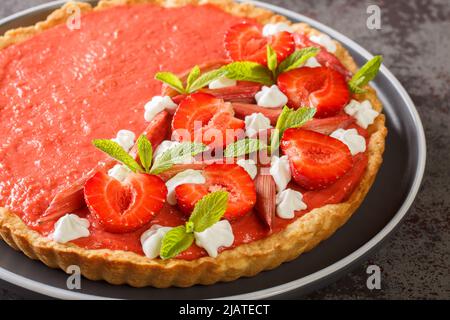 Tarte au dessert d'été avec fraises, rhubarbe, menthe et crème fouettée sur une assiette sur la table. Horizontale Banque D'Images