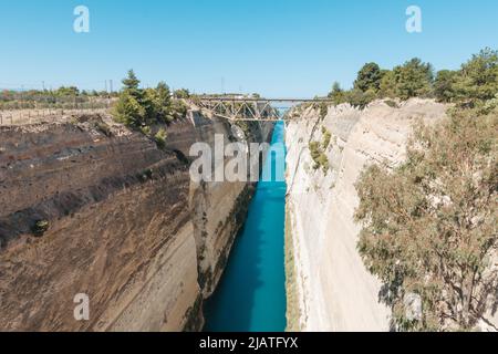 Paysage de bord de mer des deux côtés de la côte du canal de Corinthe, le bord de mer gauche brille dans une lumière de lever de soleil dorée, le côté droit est dans l'ombre, le contour du pont et le ciel bleu sur la ba Banque D'Images