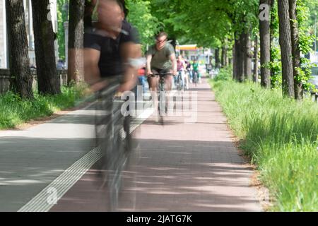 cyclistes sur une piste cyclable dans une avenue floue par une longue exposition Banque D'Images