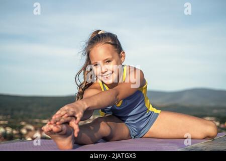 joyeux enfant dans le sport vêtements d'entraînement entraînement en plein air, étirant Banque D'Images