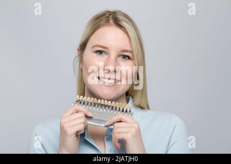 jeune femme présentant un guide d'ombre pour vérifier le placage des dents pour le blanchiment Banque D'Images