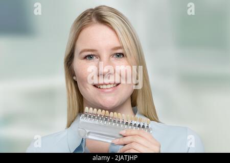 jeune femme présentant un guide d'ombre pour vérifier le placage des dents pour le blanchiment Banque D'Images