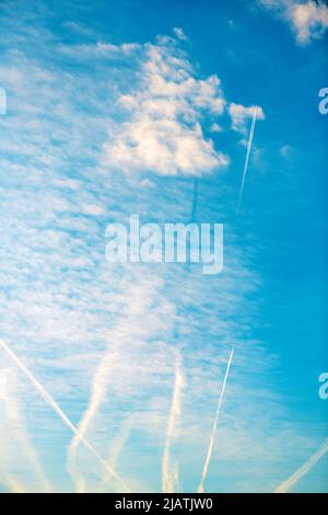 Piste de vapeur d'avion ou motif contrail sur un ciel bleu avec des nuages du dessous Banque D'Images