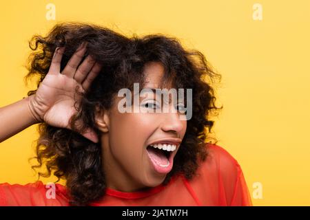 femme afro-américaine étonne montrant un geste isolé sur le jaune Banque D'Images