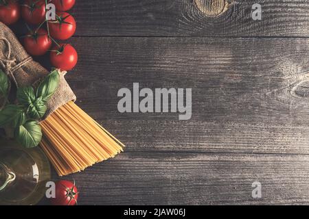 Spaghetti, tomates, huile d'olive, herbes de basilic frais sur une vieille table en bois. Place pour votre texte. Vue de dessus. Banque D'Images