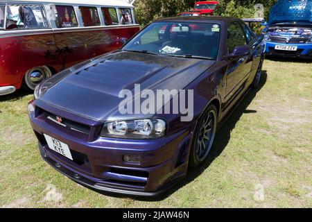 Vue des trois quarts avant d'un coupé Skyline GT-T 2000 violet et R34 de Nissan exposé au salon de l'auto Deal Classic 2022 Banque D'Images