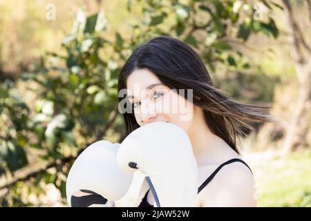 boxeur jeune femme avec gants blancs dans un parc Banque D'Images