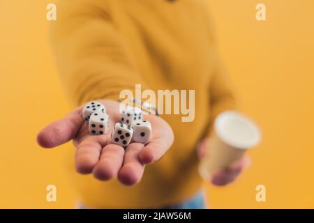 Un jeune homme européen montrant des dés dans sa main et une tasse dans un autre fond jaune copie espace studio tourné . Photo de haute qualité Banque D'Images