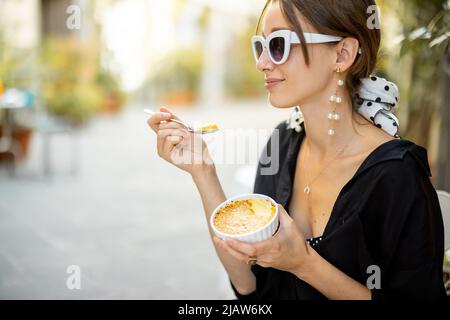 Femme mangeant un dessert avec crème brûlée au restaurant à l'extérieur Banque D'Images