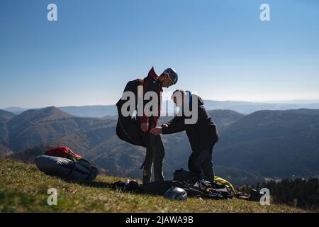 Homme aidant le pilote de parapente à se préparer au vol. Banque D'Images