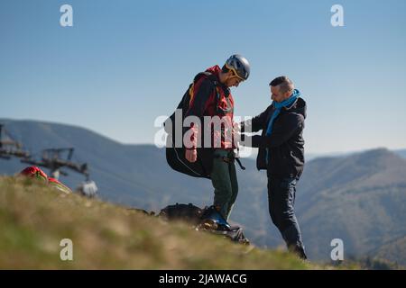 Homme aidant le pilote de parapente à se préparer au vol. Banque D'Images