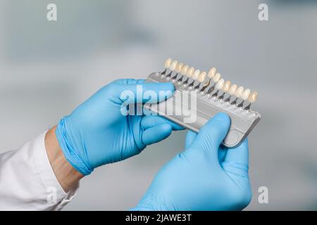 gros plan de la main du dentiste présentant un guide de l'ombre pour vérifier le placage des dents Banque D'Images