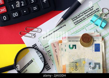 Le formulaire de déclaration d'impôt sur le revenu allemand avec des factures de stylo et d'euro européen se trouve sur le drapeau de près. Les contribuables en Allemagne utilisent la monnaie euro comme principal moyen de payer ta Banque D'Images