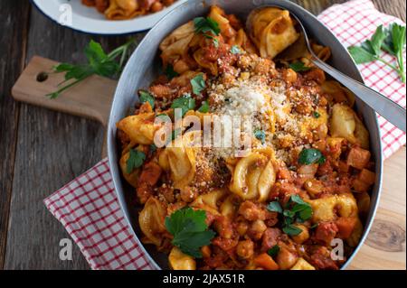 Pâtes avec sauce tomate, pois chiches, pancetta, légumes et parmesan. Servi dans une poêle rustique sur fond de table en bois. Vue de dessus Banque D'Images